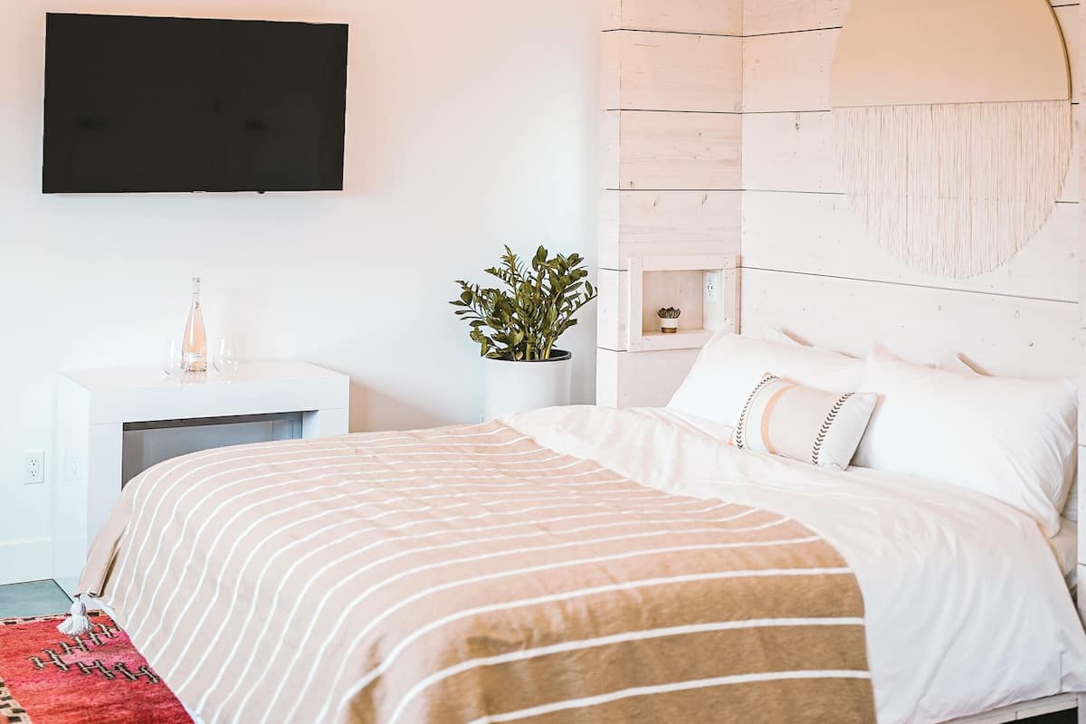 Une chambre à coucher comprenant un lit, un luminaire suspendu, un téléviseur fixé au mur et un élément décoratif circulaire fixé au mur.