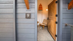 A wooden door with a number '9' sign, a surfboard decoration, and a chair inside. - Surf Lodge (Stinson Beach)