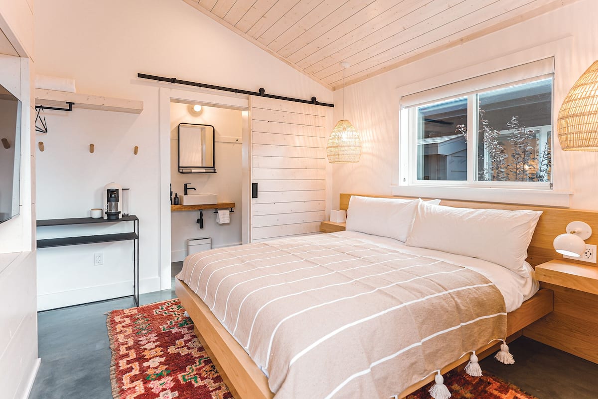 Une chambre à coucher comprenant un lit, une table de chevet, une fenêtre et un petit espace bureau avec une chaise.