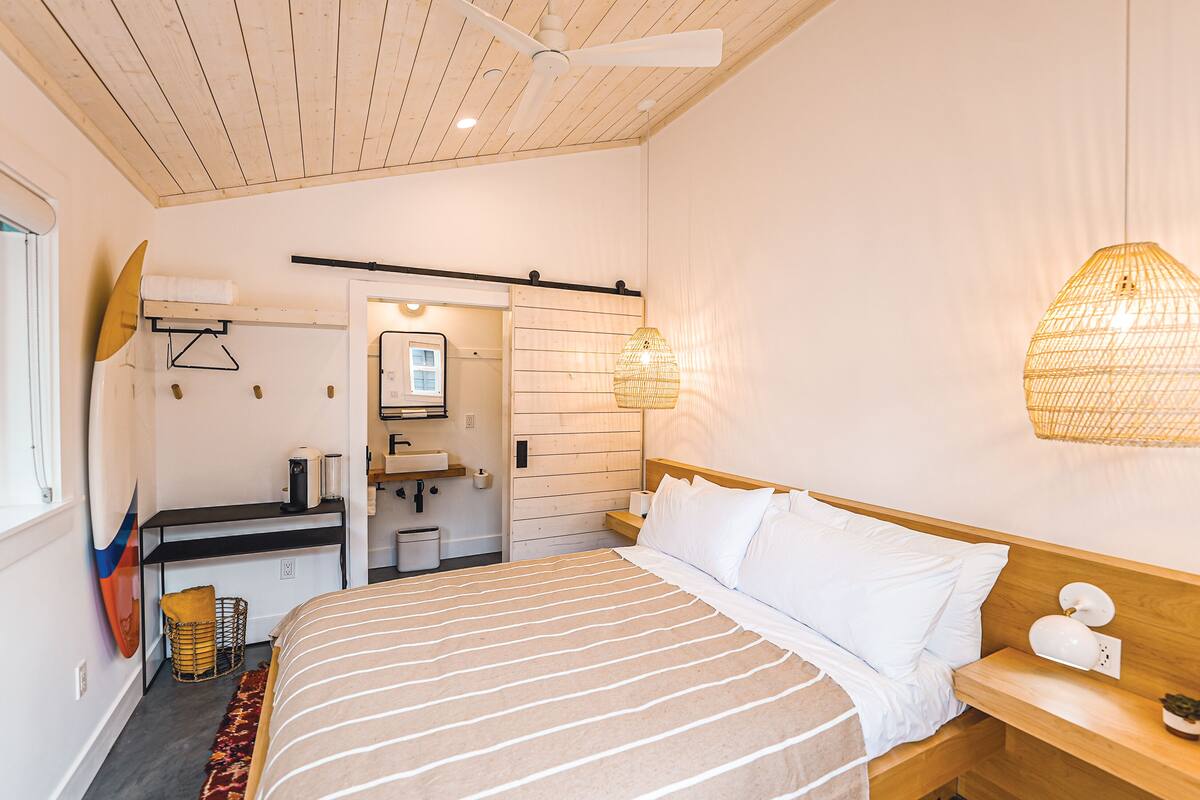 Une chambre à coucher avec un lit, une table de chevet et un ventilateur de plafond.
