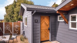 A house with a wooden door, a small porch with a bench, and a fenced backyard. - Surf Lodge (Stinson Beach)