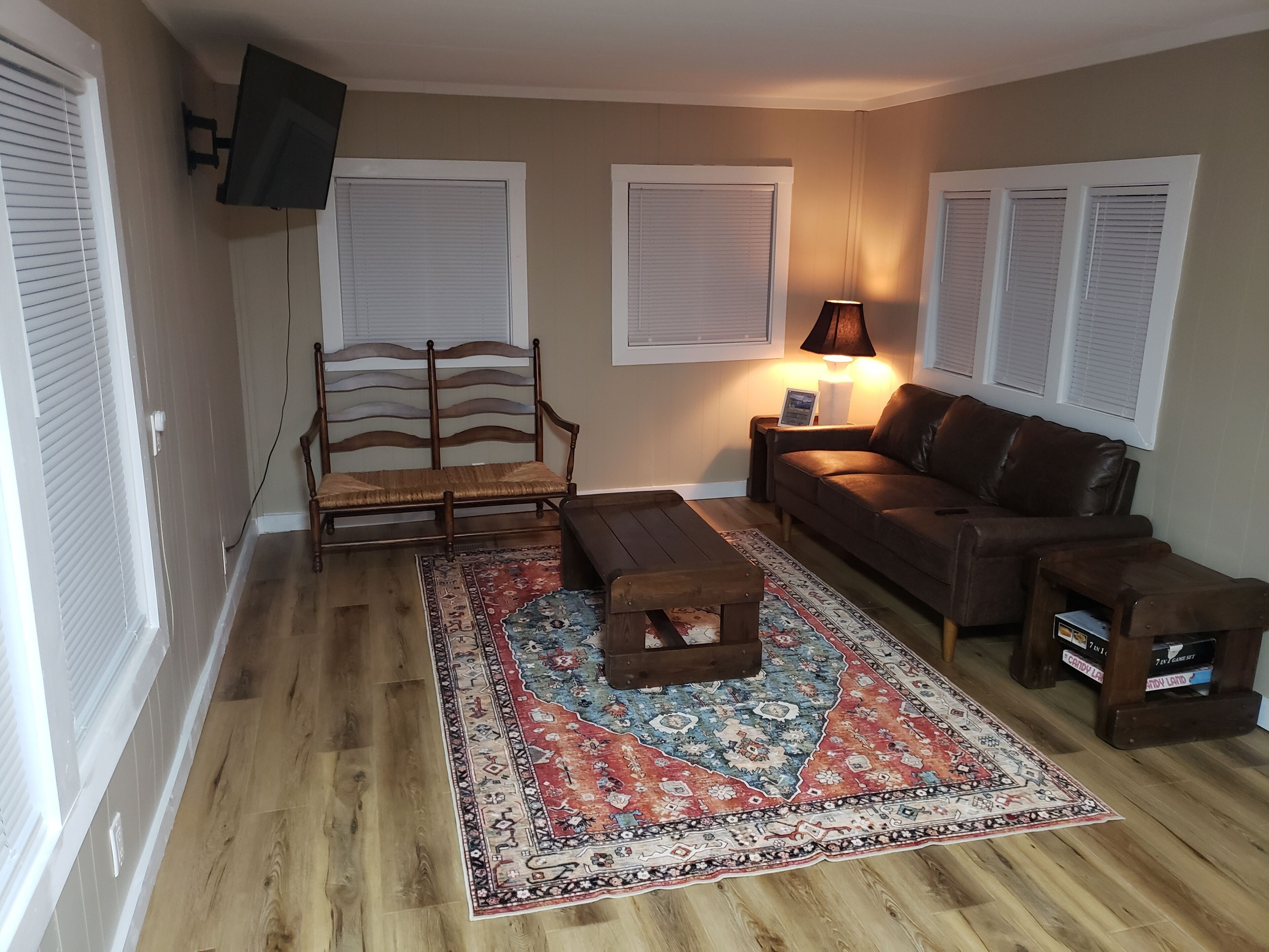 A living room with a wooden floor, a sofa, a coffee table, a rug, and a lamp.