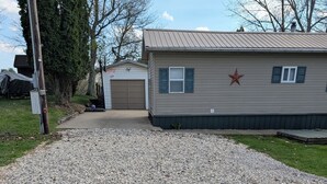 A gravel driveway leading to a mobile home with a star decoration on the side. - Camp Fishbone - Our place at the Lake (Freeport)