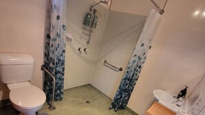 A compact bathroom with a toilet, shower, and sink. - Queenstown Copper Country Cabins (Queenstown)