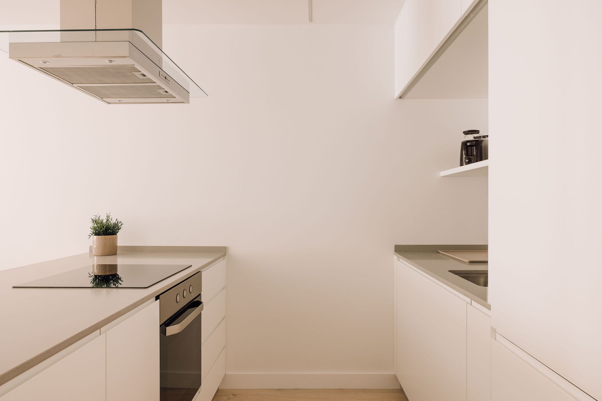 A modern kitchen with white cabinetry, a stainless steel sink, and a built-in oven.