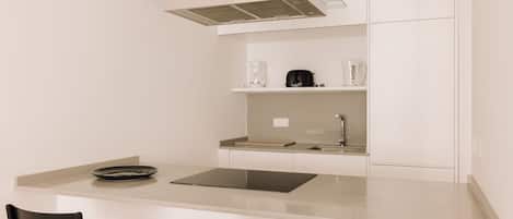 Una cocina compacta con una isla, dos sillas, una cafetera y un hervidor.