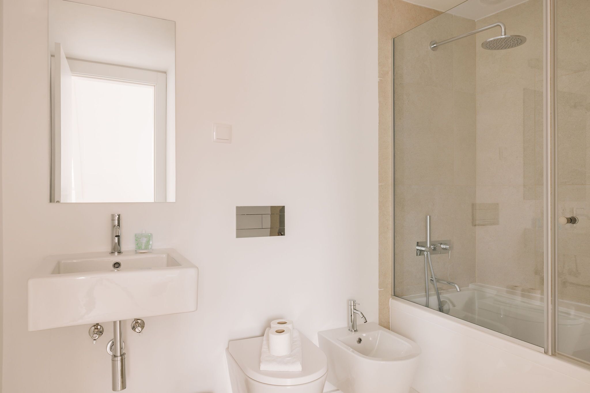 Un baño moderno con lavamanos, inodoro, bidé y ducha con mampara de vidrio.