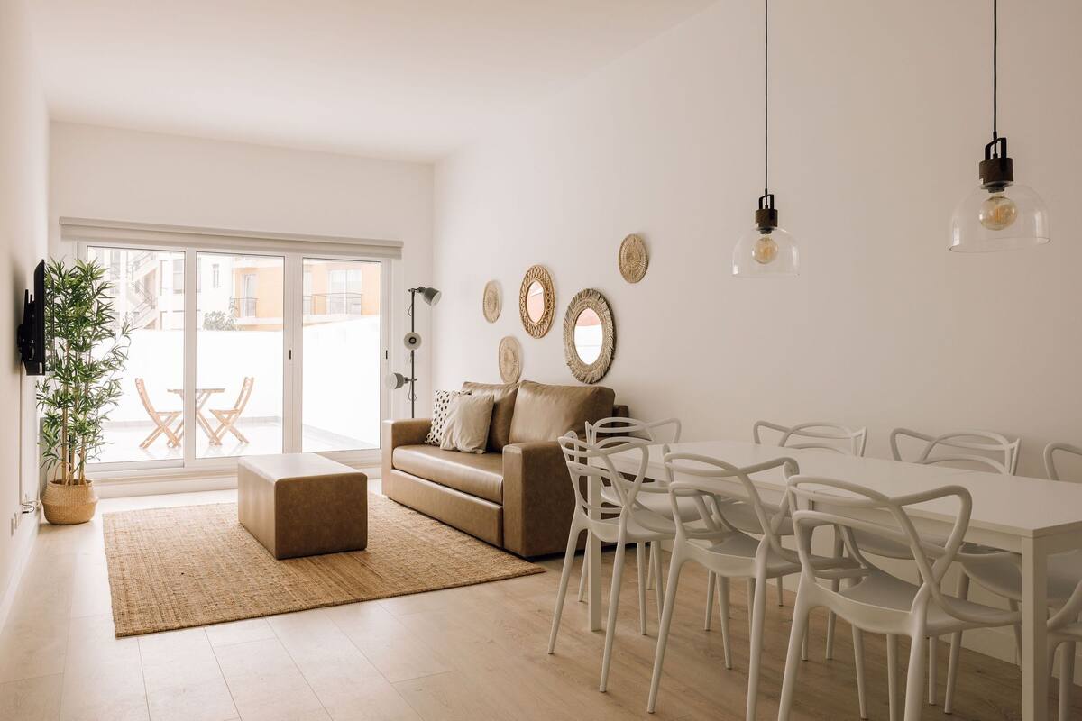 A modern living room with a sofa, dining table, chairs, and decorative wall art.