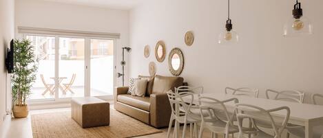 A modern living room with a sofa, dining table, chairs, and decorative wall art.