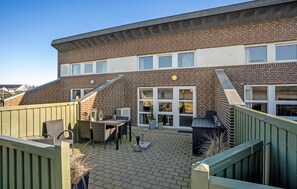 A brick building with a patio area featuring outdoor furniture and a small garden.
