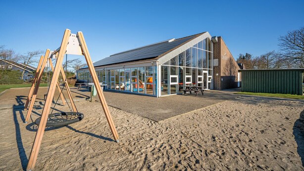 A modern building with large glass windows and a sloped roof. - Cozy apartment in Hemmet with sauna (Hemmet)