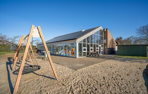 A modern building with large glass windows and a sloped roof. - Cozy apartment in Hemmet with sauna (Hemmet)