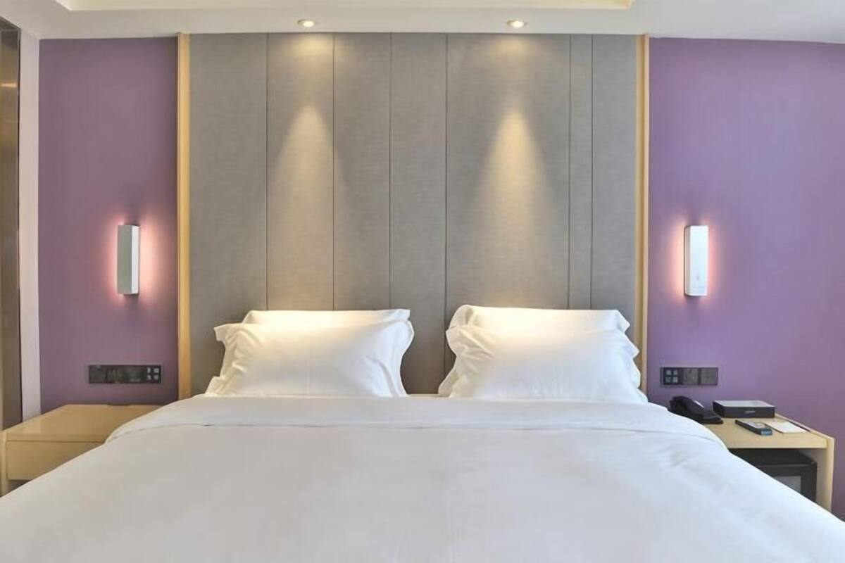 A hotel room with a large bed, two bedside tables, and wall-mounted lighting.