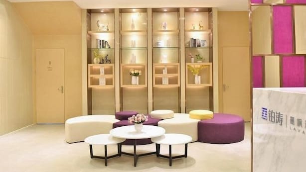 A modern hotel lobby with a seating area, a reception desk, and a decorative wall with shelves. - Lavande Hotel (Guangzhou Jiahe Wanggang Metro Station) (Guangzhou)