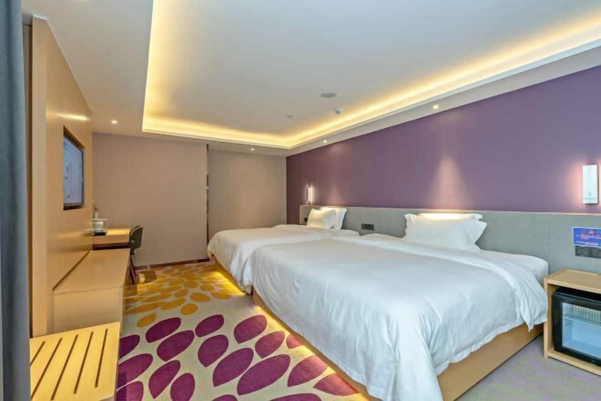 A hotel room with a bed, bedside table, and a television.