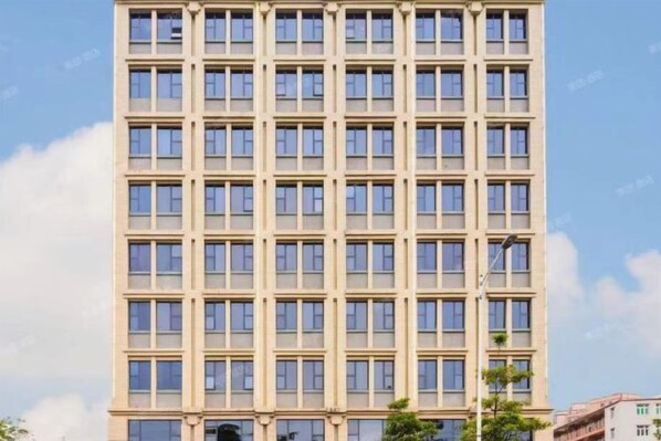 A tall, beige building with a grid of windows and a flat roof.