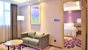 A hotel room with a sofa, a small table, a bed, and a painting on the wall. - Lavande Hotel (Guangzhou Jiahe Wanggang Metro Station) (Guangzhou)