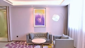 A modern hotel room with a sofa, armchair, and a small table. There is a painting on the wall and a lamp on the side. - Lavande Hotel (Guangzhou Jiahe Wanggang Metro Station) (Guangzhou)