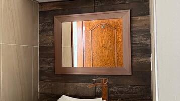 A bathroom with a wooden vanity, a mirror, and a white sink.