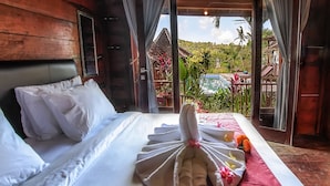 A hotel room with a bed, white linens, a towel arrangement, and a view of the outdoors. - The Dara Hill (Penida Island)