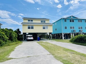 Edificio de dos pisos con acceso a garaje, fachada azul y un letrero que dice 'SHAVE HIRINGS'.