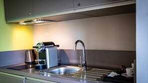 A modern kitchen with a stainless steel sink, a coffee machine, and a kettle.