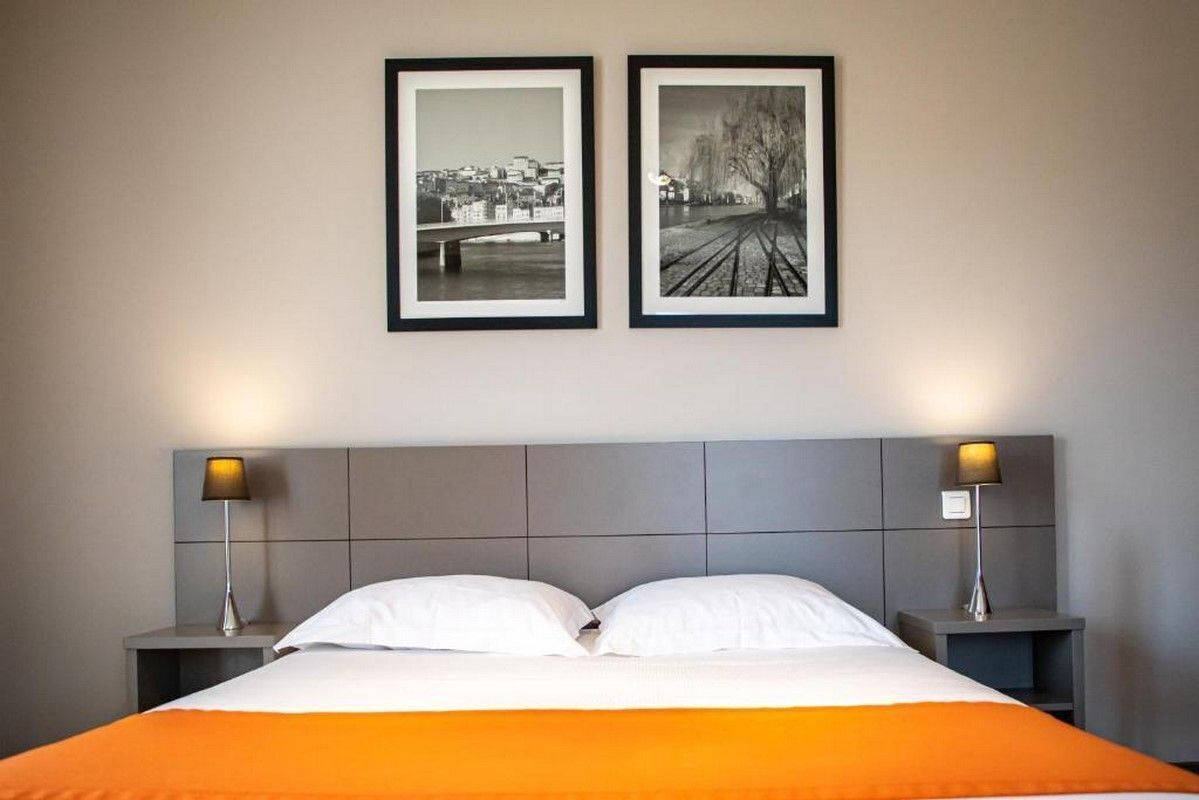 Habitación de hotel con una cama, dos mesitas de noche y dos cuadros en la pared.