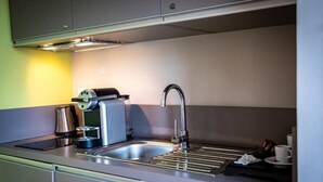 Une cuisine moderne équipée d’un évier en acier inoxydable, d’une machine à café et d’une bouilloire.