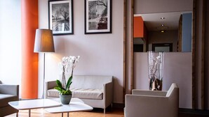 A modern lobby with a sofa, chairs, a coffee table, a lamp, and two framed photographs on the wall. - À 10 min du métro | Terrasse + Vue panoramique (Lyon)