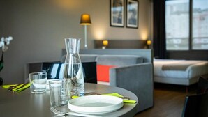 A modern hotel room with a dining area, a sofa, and a bed. - À 10 min du métro | Terrasse + Vue panoramique (Lyon)
