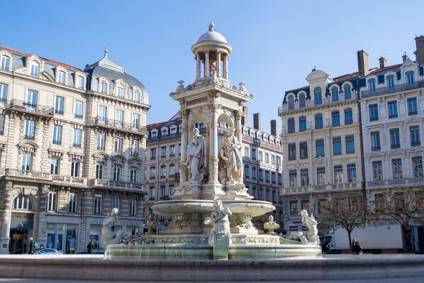 A historic fountain with statues, surrounded by classical architecture.