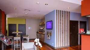 A modern interior with a dining area, kitchen, and a TV mounted on the wall. - À 10 min du métro | Terrasse + Vue panoramique (Lyon)