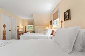 Une chambre d’h ôtel avec deux lits, une fenêtre avec des stores, une porte et une lampe sur la table de chevet.