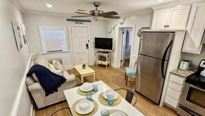 A compact living space with a dining area, kitchenette, and a television.