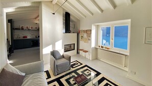 Een ruime woonkamer met een moderne bank, een geometrisch vloerkleed en uitzicht op zee door een groot raam.