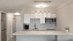 Una cucina moderna con un'isola grande, elettrodomestici in acciaio inossidabile e illuminazione a sospensione.