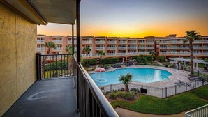 Un hotel con piscina, diversi balconi e vista sul tramonto.
