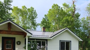 A single-story house with a front porch, a large window, and a bicycle leaning against the wall.