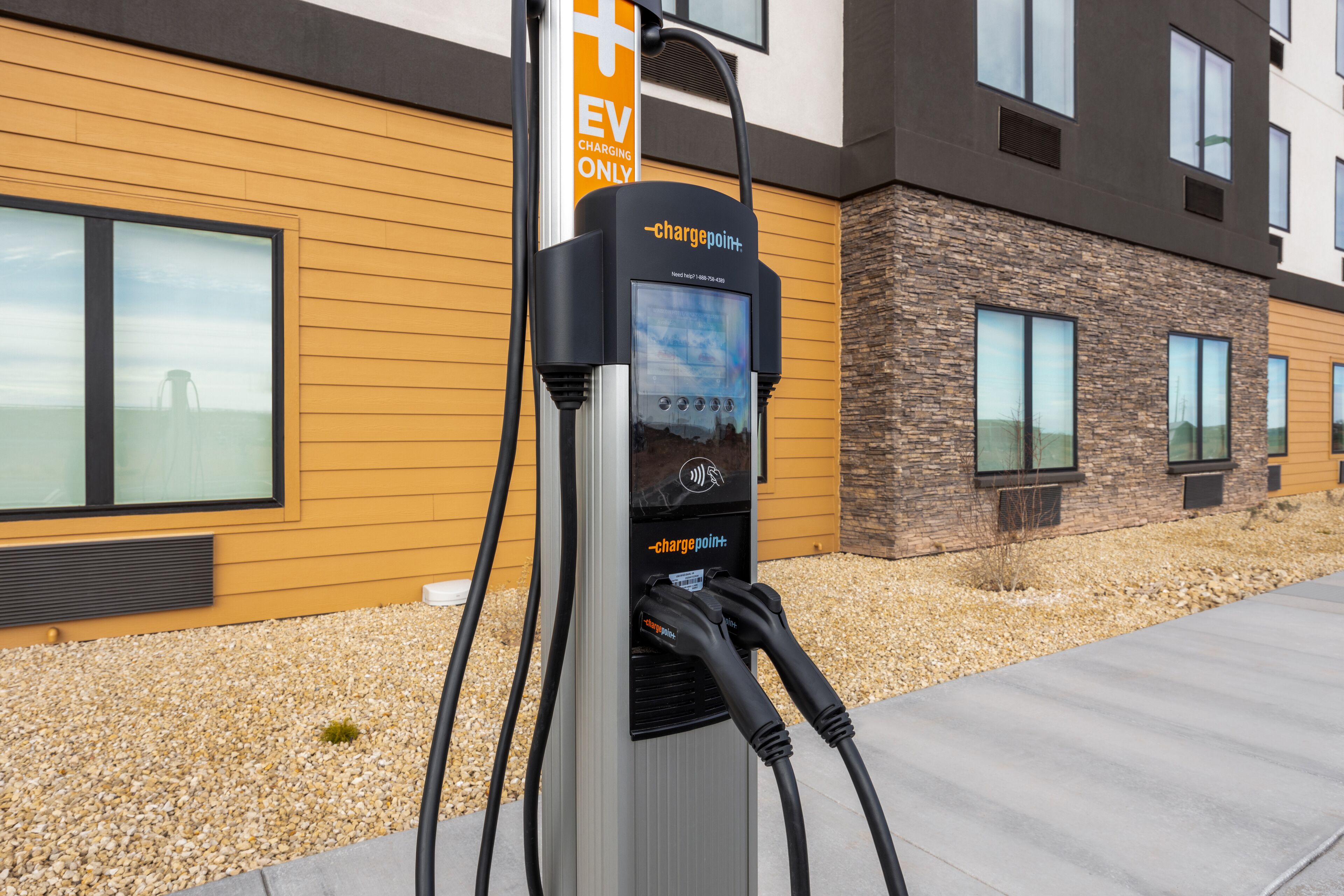 An electric vehicle charging station with a modern building in the background.