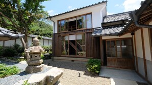 A traditional Japanese-style building with large windows, a wooden door, and a stone lantern in the garden. - SATOYAMA HOTEL KANENONE TAMBA (Tamba)