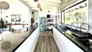 A modern kitchen with a central island, pendant lighting, and a view of the outdoors. - Hare Mahatu (Hanga Roa)