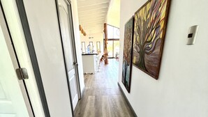 A hallway with wooden flooring, a white door, and a painting on the wall. - Hare Mahatu (Hanga Roa)