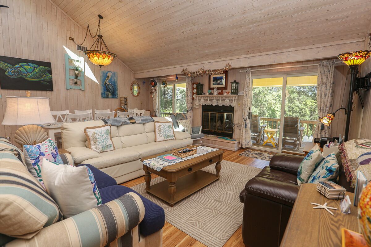 A cozy living room with a fireplace, wooden furniture, and a large window.