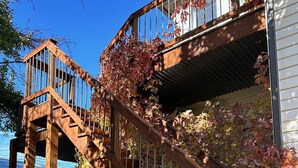 A wooden staircase leading to a balcony with a metal railing, surrounded by autumn foliage. - Gorgeous downtown beauty! 2min walk to local restaurant's/Main Street Montrose (Montrose)
