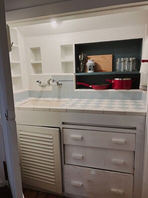 Kitchen features a classic design with a white sink, chrome faucet, and wooden cutting board.