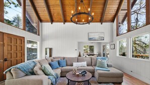 A spacious living room with a large sectional sofa, a round coffee table, and a wooden ceiling.