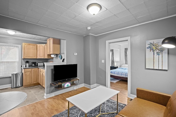 A compact living space with a kitchenette, a dining area, and a bedroom.