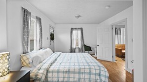 A bedroom with a bed, a bedside table, a chair, and a door leading to another room. - Pet Friendly 1BR in Ohio City (Cleveland)