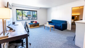 A modern hotel room with a desk, chair, blue sofa, and a small coffee table. - Spacious Studio near Downtown LA (Los Angeles)
