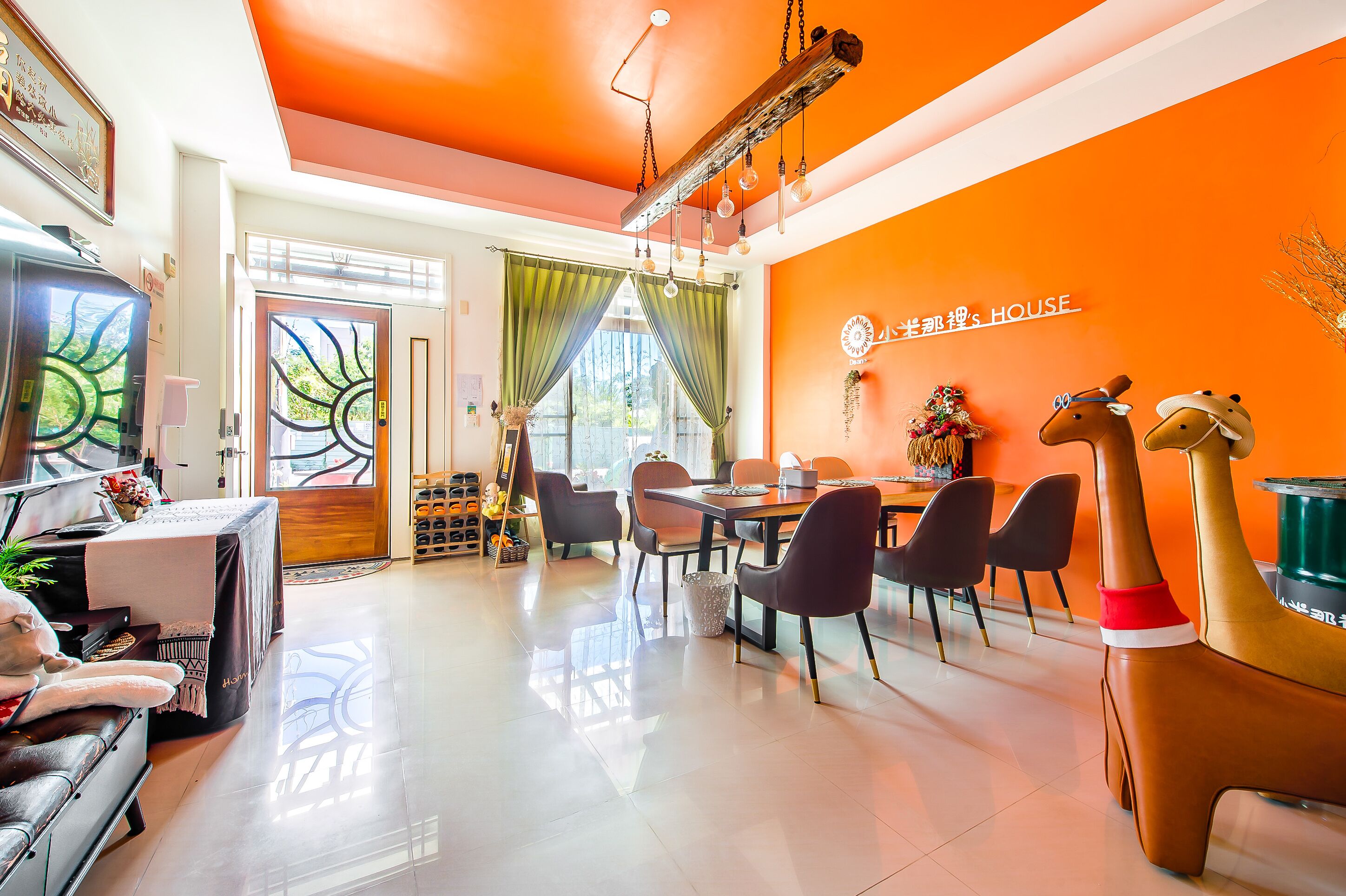 Uma área de refeições moderna com uma parede laranja vibrante, teto de madeira e mesa posta para quatro pessoas.